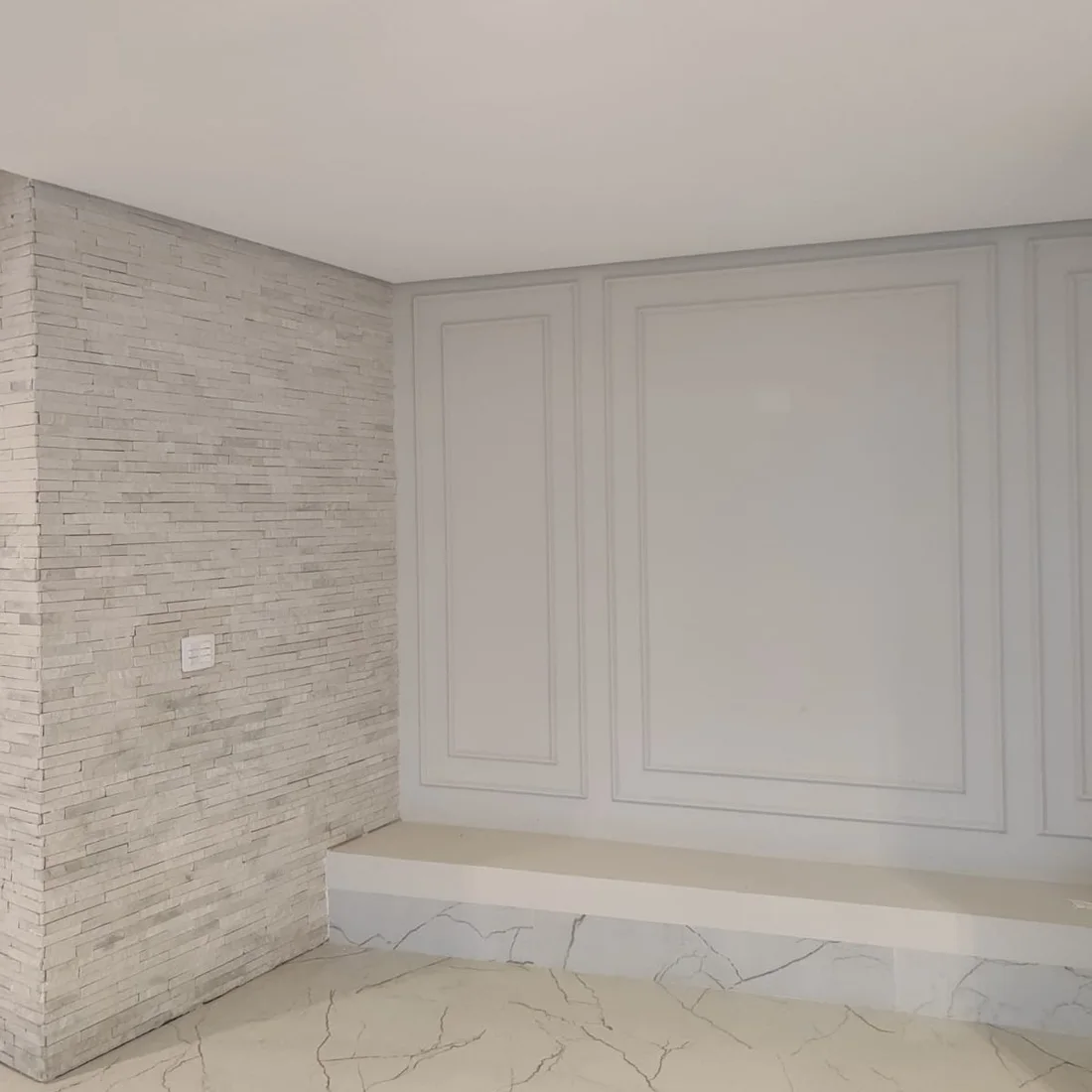 Ambiente de casa reformada com parede em pedra e porcelanato